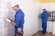 Foto FotoMural Workteam installing electrics in a tiled room